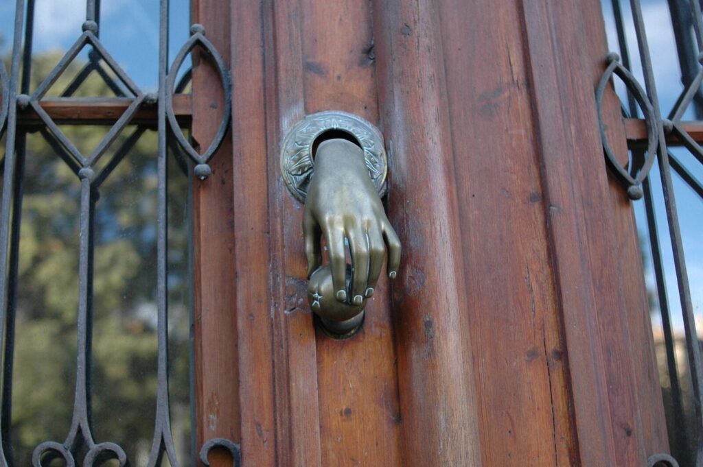 Porte d'entrée en bois avec heurtoir et grilles en fer forgé